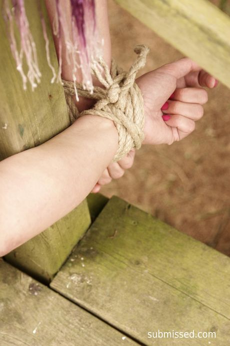 金髮美女 Deedee 露出她巨大的乳房，嘴巴在外面被堵住