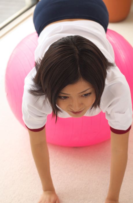 Den asiatiske pige Mami Matsuyama leger med en volleyball, mens hun har en sports-bh på