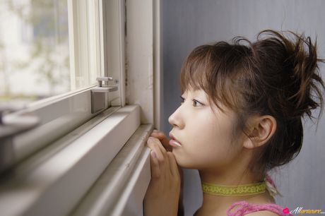 Brown eyed Japanese babe shows off her small tits and bald pussy