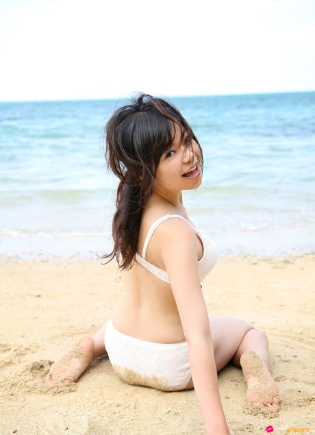 亞洲女孩 Mana 在海灘上展示她迷人的胸部並穿著比基尼擺姿勢