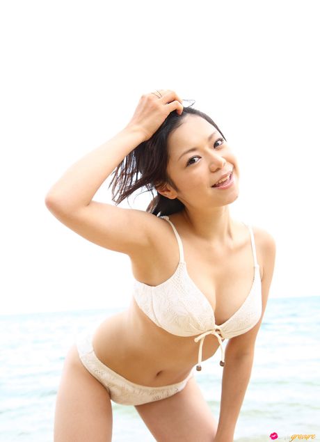 亞洲女孩 Mana 在海灘上展示她迷人的胸部並穿著比基尼擺姿勢