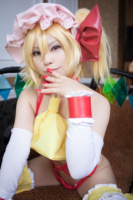 金髪の日本人女性ラット・サクラが、キッチンでモデルをしながら帽子と羽を身に着けている