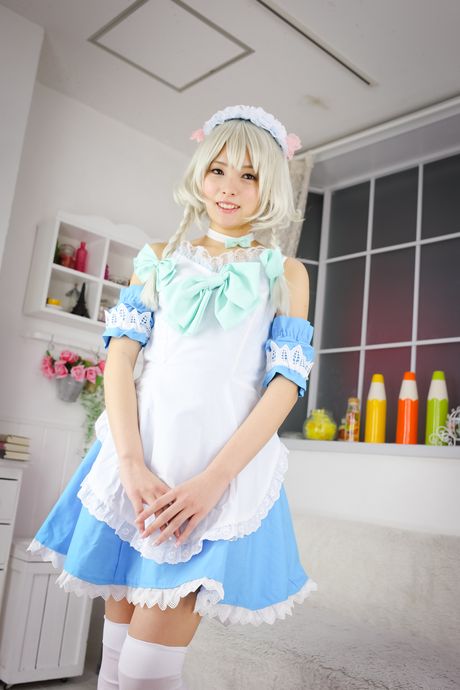 Asiatisk pige i en flæsekjole og hvide strømper stripper og poserer