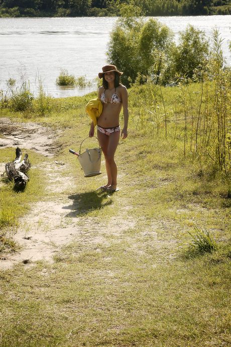 Slank teenager Elela blotter sig på en sandet flodbred under solo-action