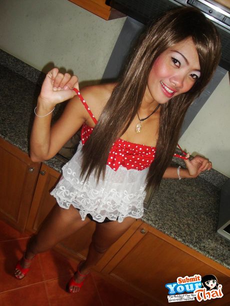 Asiatisk søde Fa sutter på en slikkepind, mens hun bliver nøgen i et køkken