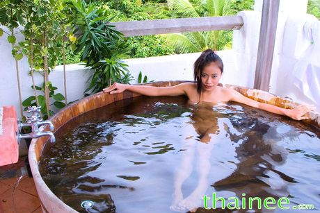 Asian cutie Thainee goes nude on a chair in a backyard