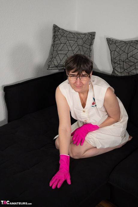 Moden tysk dame i et hvidt forklæde og latexhandsker poserer solo