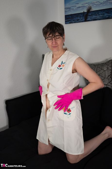 Moden tysk dame i et hvidt forklæde og latexhandsker poserer solo