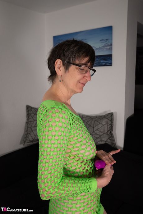 熟したドイツ人女性リラは、緑のドレスを着て紫色のディルドで彼女の猫を弄ぶ