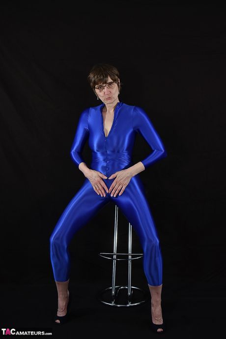 Moden tysk dame i en latex bodysuit, der afslører sine små bryster og skaldede fisse