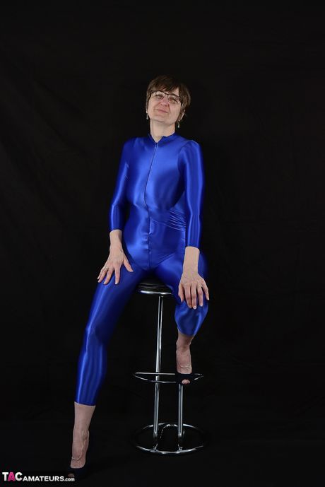 Moden tysk dame i en latex bodysuit, der afslører sine små bryster og skaldede fisse