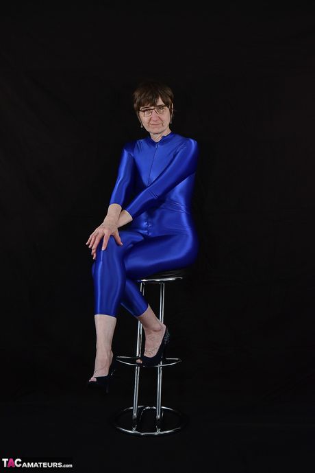 Moden tysk dame i en latex bodysuit, der afslører sine små bryster og skaldede fisse