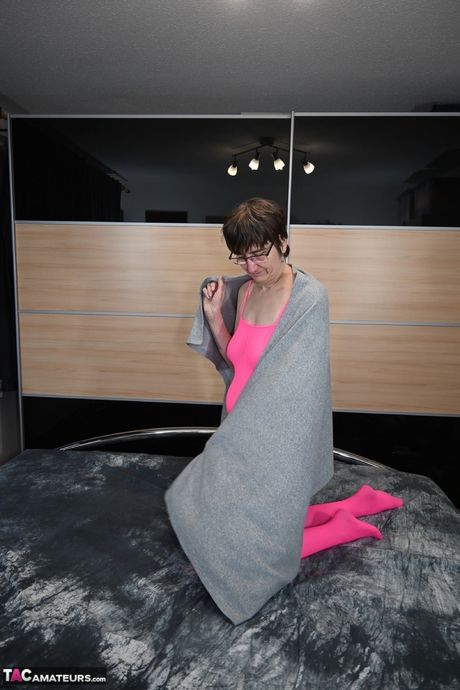 戴眼鏡、穿著粉紅色內衣的德國成年女士用手指撫摸自己淫蕩的陰部