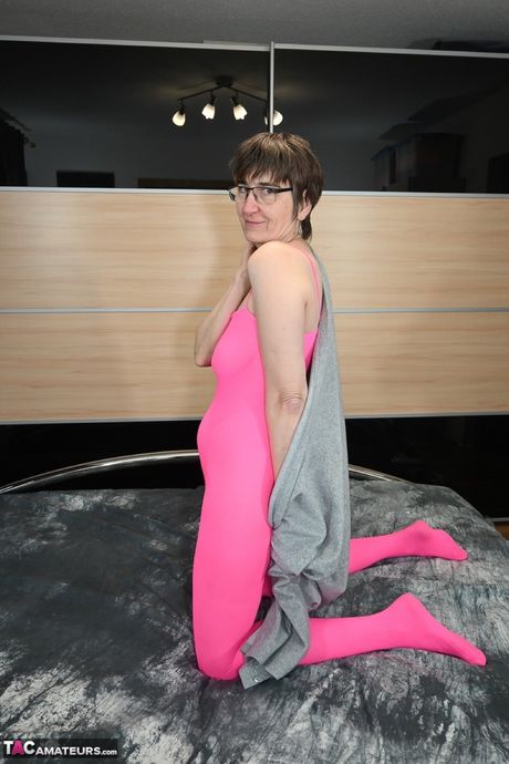 戴眼鏡、穿著粉紅色內衣的德國成年女士用手指撫摸自己淫蕩的陰部