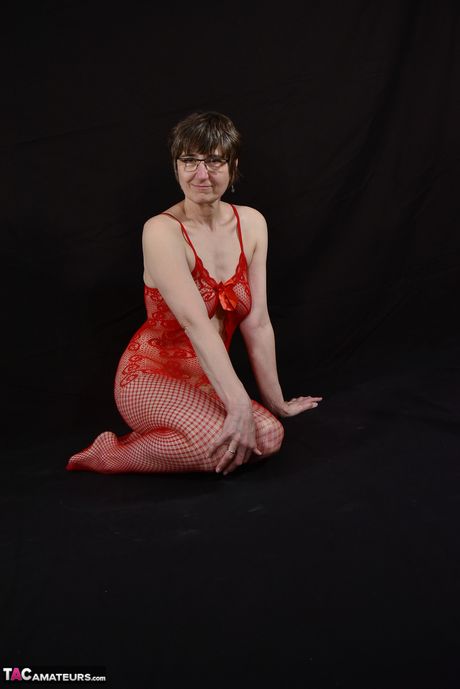 Voksen tysk dame i fiskenet og briller leger med sin fisse i et rødt catsuit