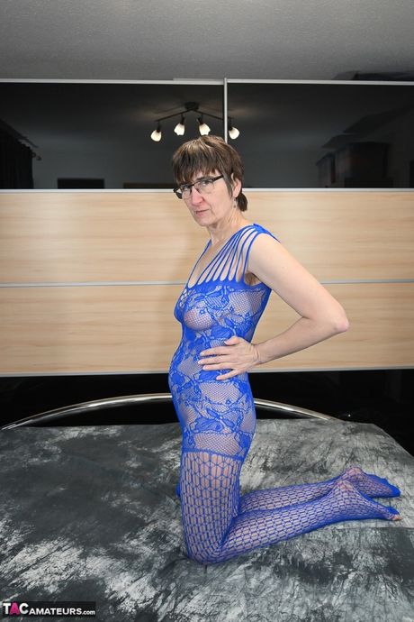 戴眼鏡和漁網襪的德國成年女士在單人表演中玩弄她的陰部