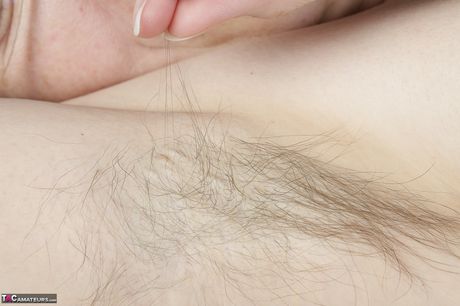 苗條的成熟女士，有著扁平的乳房和多毛的陰部，玩弄她的陰部