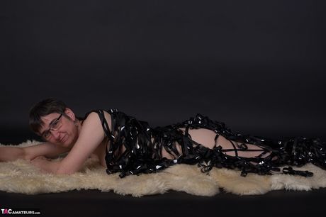 戴著眼鏡和靴子相當成熟的人在黑暗中裸體擺姿勢