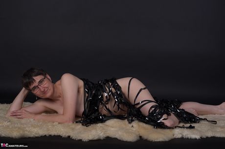 戴著眼鏡和靴子相當成熟的人在黑暗中裸體擺姿勢