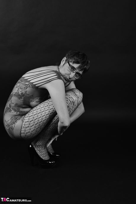 Voksen tysk dame i catsuit og briller stripper ned til hendes strømper