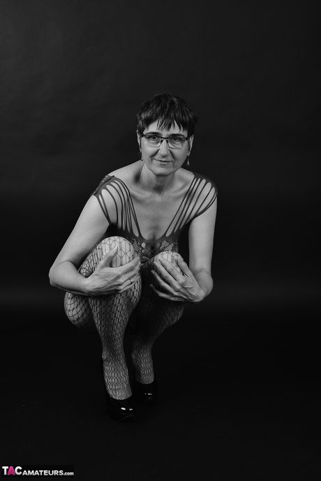Voksen tysk dame i catsuit og briller stripper ned til hendes strømper