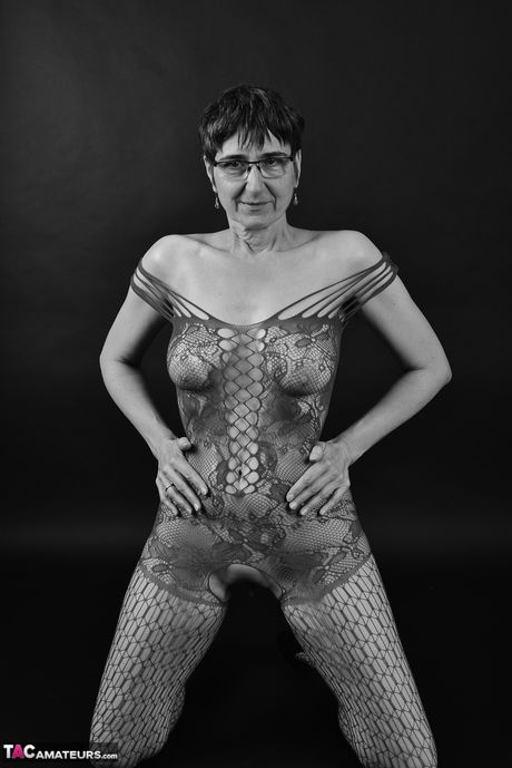 Voksen tysk dame i catsuit og briller stripper ned til hendes strømper