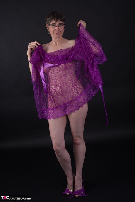 メガネと下着姿のドイツ人成人女性が紫色のドレスを脱いで裸のモデルに