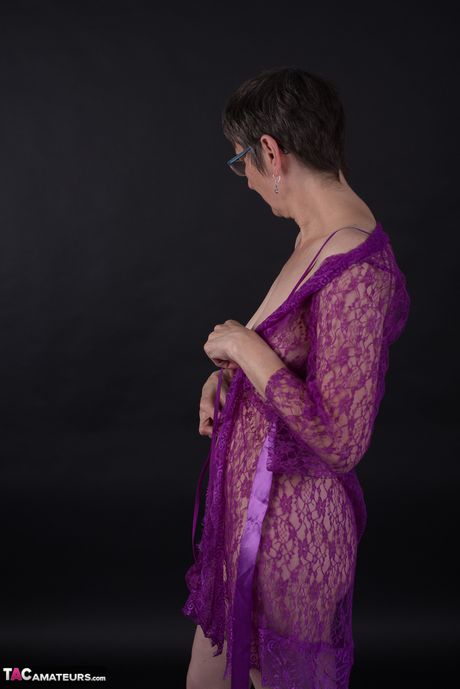 メガネと下着姿のドイツ人成人女性が紫色のドレスを脱いで裸のモデルに