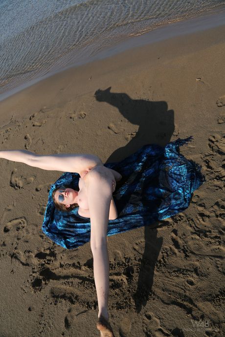 Nøgen ukrainsk coverpige Emily Bloom viser sin skaldede fisse frem på et tæppe på en sandstrand