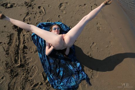 Nøgen ukrainsk coverpige Emily Bloom viser sin skaldede fisse frem på et tæppe på en sandstrand