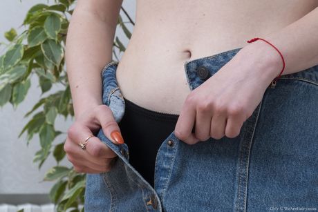 深色頭髮的少女赤身裸體後用捲曲的手指張開她的陰部