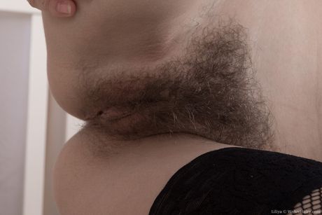 Glamourmodel Liliya fingrer sin behårede fisse på en stol i strømpebukser